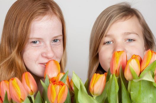 two young girls are holding pink orange tulips