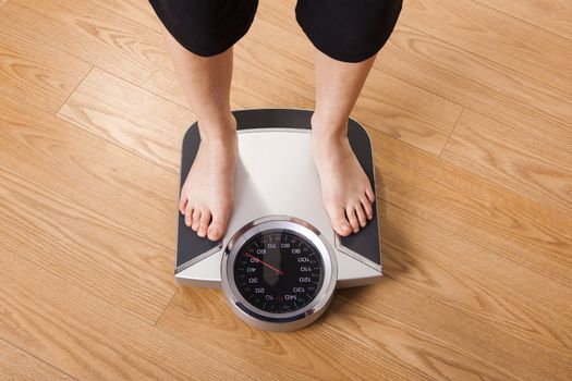 Athletic young girl measuring her weight on a scale