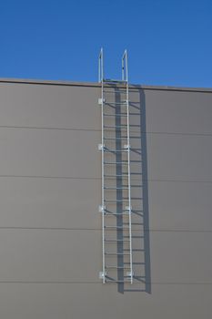 Steel emergency ladder going up from earth to blue sky.