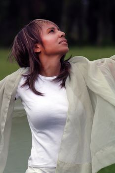 A beautiful mature black woman soaks up some atmosphere and celebrates with a swatch of sheer fabric outdoors.