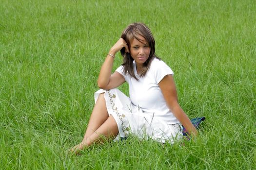 A lovely mature black woman in a grassy field, looking into the camera with a relaxed, pleasant facial expression.