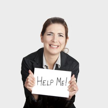 Stressed business woman imploring for help, holding a cardboard with the message "Help"