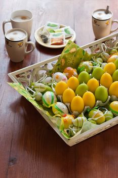 Yellow and green easter egg decoration on table and mugs with coffee