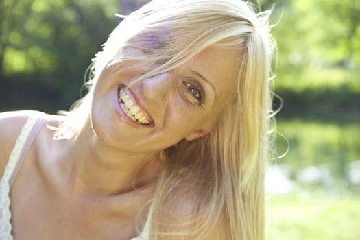 Smiling blond woman resting in green environment