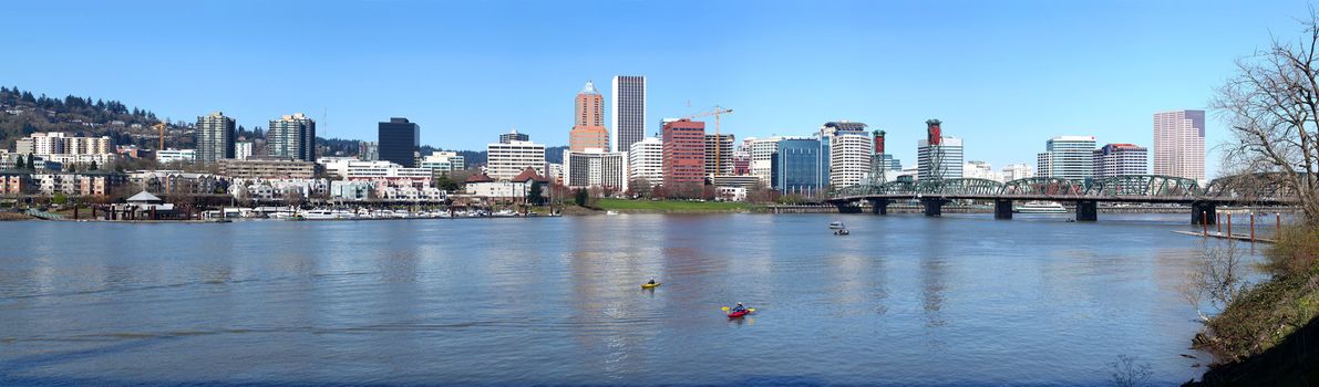 A panoramic view of the city of Portland Oregon and kayaks in the river.