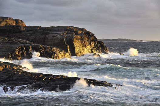 Evening sun and large waves hits the rocks