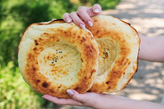 Two traditional flat cakes from tandoor in hands.