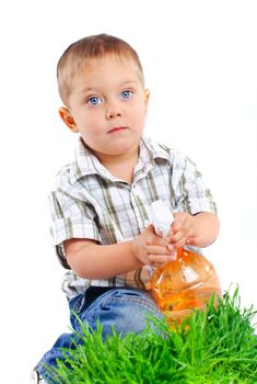 Cute boy watering the green grass. In the studio