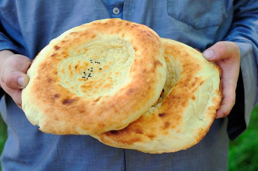 Two traditional flat cakes from tandoor in hands.