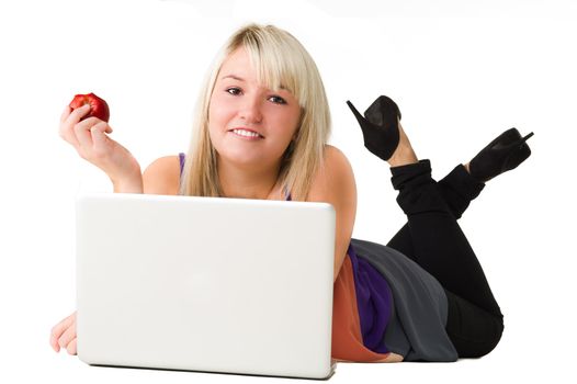 Young beautiful smiling girl using here laptop while eating an apple. Over white background