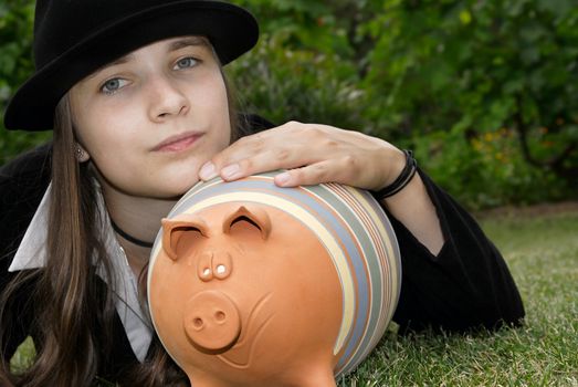 Girl in suit with piggy bank in the park