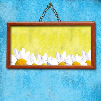Picture frame hanging photo of daisies in an old blue wall