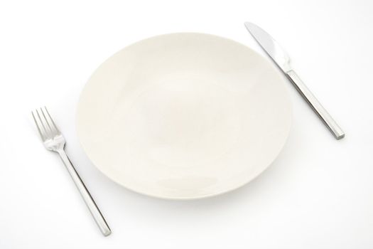 top view of white plate, fork and knife, restaurant tableware