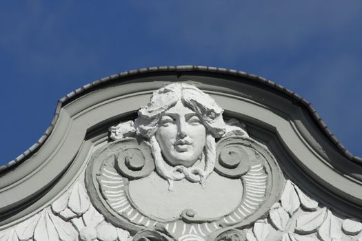 Steinrelief mit Frauenkopf mit blauem Himmel im Hintergrund	
Stone relief with woman's head with blue sky in the background