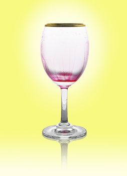 Red wine glass is empty on yellow background