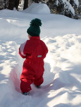 Small child in warm winter clothes in the snow