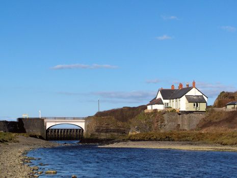 An isolated white house and a bridge on a river near Aberystwyth, Wales.