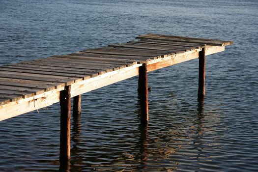 Old wooden jetty with steel supports on a river
