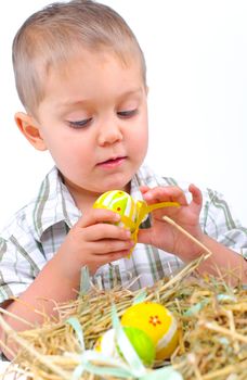 Little boy playing with easter eggs in basket. Focus on the boy