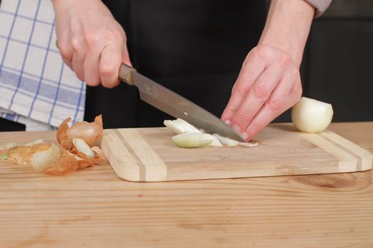 Freshly washed white onion on cutting board with knife.