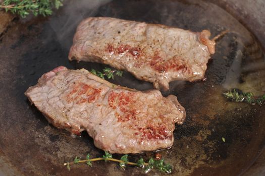 Beef steak cooking in a iron grill pan.