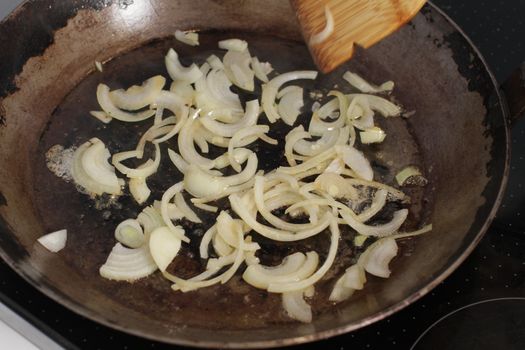 frying sliced white onions in an old pan