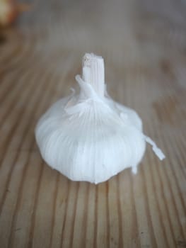 Whole garlic and clove on a wooden surface.