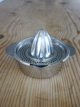 Metal citrus squeezer on a wooden table