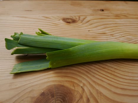 fresh leek lying on wooden board on white background