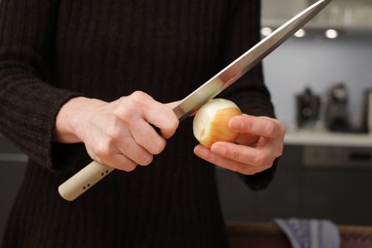 Freshly washed white onion on cutting board with knife.