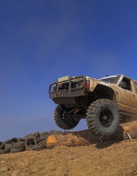 Off road car passing a tree trunk obstacle during a competition.