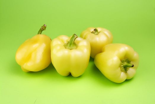 Yellow peppers on green background, studio shot