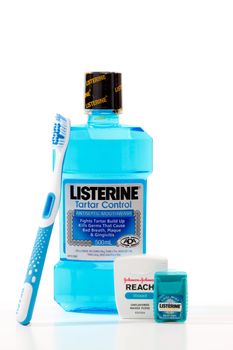 Four dental hygiene products made by Johnson and Johnson.   Products from left to right are, Reach toothbrush, Listerine Tartar Control antiseptic mouthwash, Reach waxed dental floss, and Listerine Pocketpaks Cool Mint breath strips.  Photographed in studio on a white background.  Editorial use only