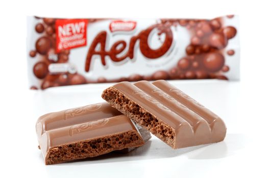 Nestle Aero chocolate bar Original 40g (450kj)  Showing product packaging at rear and chocolate bar content in focus in the foreground.  Milk chocolate with a light aerated bubbly centre.  Photographed in studio on a white background.