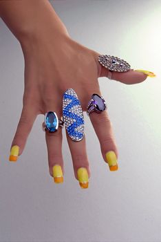 Hand showing big rings on fingers, colored nails