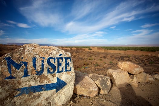 Blue arrow and museum painted on a stone in a small desert village in the south of Morocco