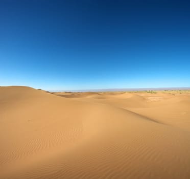 Sahara desert close to Merzouga in Morocco with blue sky and clouds