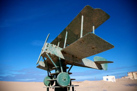 Green plane on a green brick construction with blue sky, memorial to Saint-Exupery