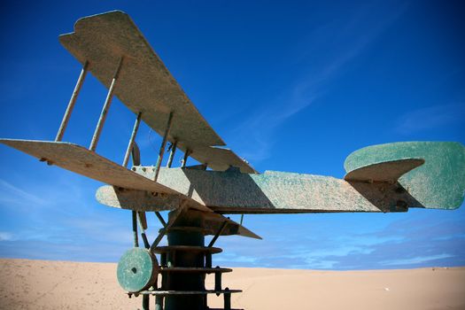 Green plane on a green brick construction with blue sky, memorial to Saint-Exupery