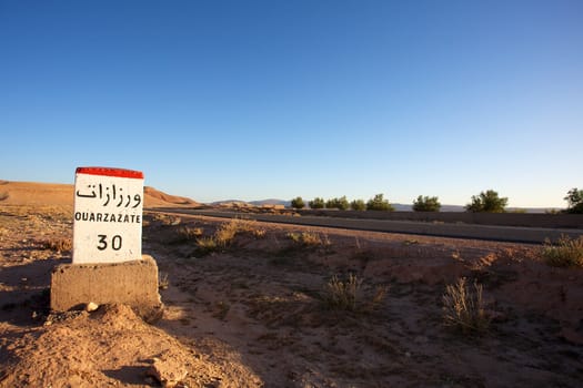 Road Sign to Ouarzazate in Morocco with blue sky