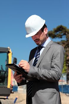 young man with hardhat and pen on building site