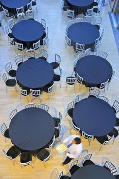 Overhead view of a restaurant with empty tables. A waiter passes, motion blur on the man.