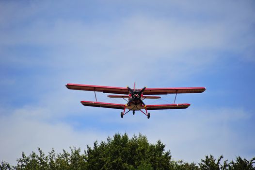 An Antonov AN-2 biplane head-on as it approaches an airfield on short finals. Space for text in the sky.