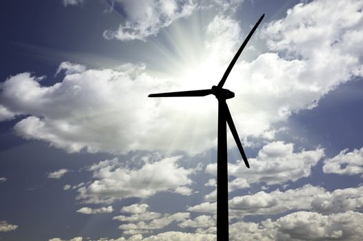 Silhouetted Wind Turbine Over Dramatic Sky and Clouds.
