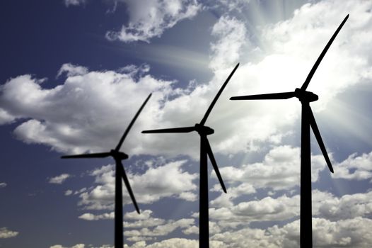Silhouetted Wind Turbines Over Dramatic Sky and Clouds.