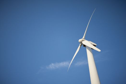 Single Wind Turbine Over Dramatic Blue Sky and Clouds.
