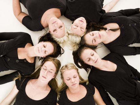 Group of Young Women with closed eyes lieing in a circle on white background