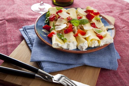 Ricotta stuffed cannelloni topped with red peppers, basil and Parmesan cheese flakes.