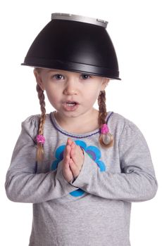 A young girl with a black metal style bowl hat on her head.  She is bowing before the viewer and pretending to be Chinese.