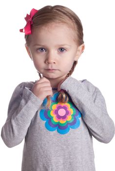 A sweet little child is holding her braids and being shy.